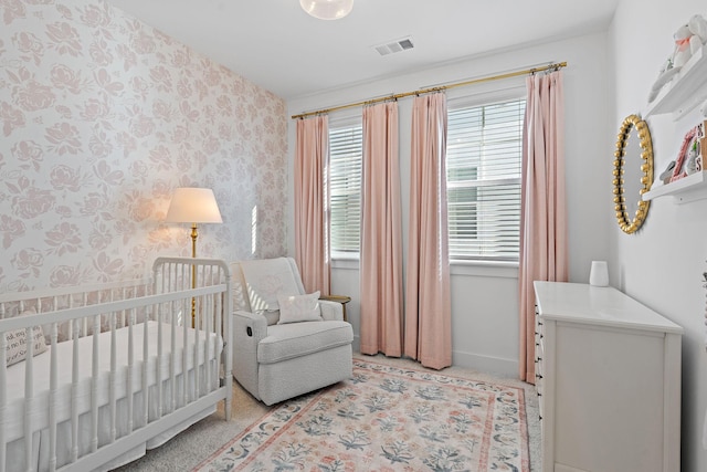 bedroom with a crib, wallpapered walls, baseboards, and visible vents