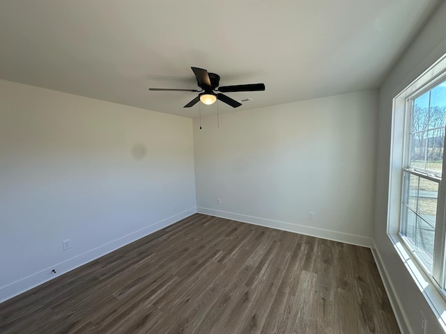 spare room featuring dark wood-style floors, baseboards, and a ceiling fan