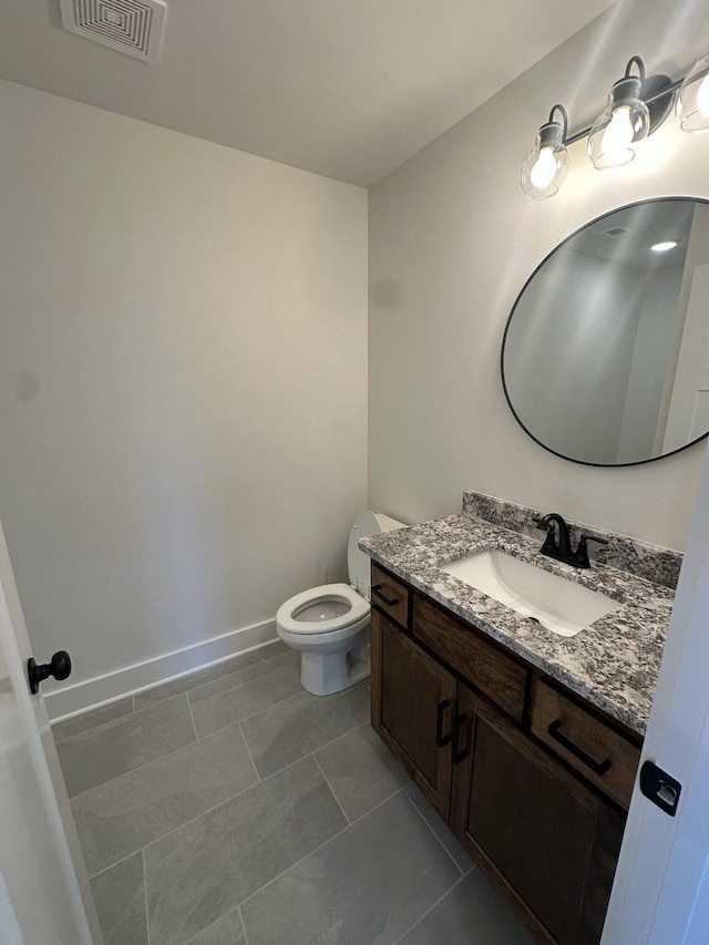 half bath featuring toilet, vanity, visible vents, baseboards, and tile patterned floors