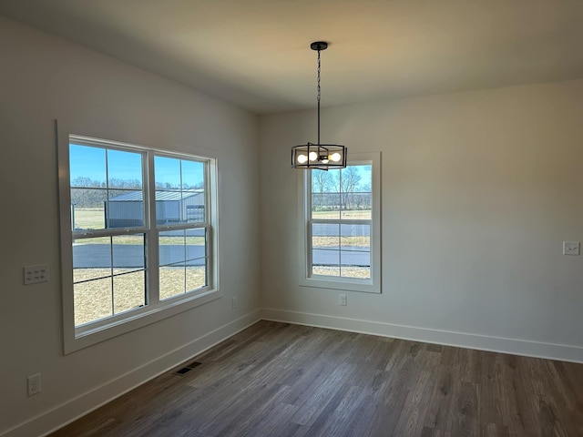 spare room featuring a wealth of natural light, visible vents, a notable chandelier, and baseboards