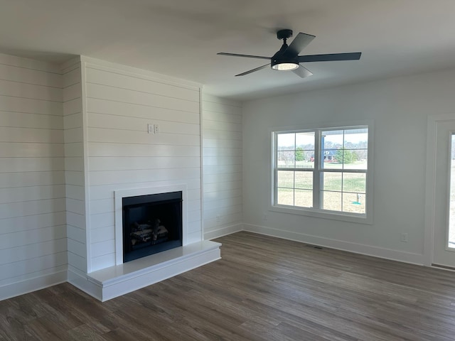 unfurnished living room with dark wood-type flooring, visible vents, a fireplace, and baseboards