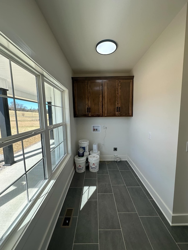 clothes washing area with hookup for a washing machine, cabinet space, hookup for an electric dryer, dark tile patterned flooring, and baseboards