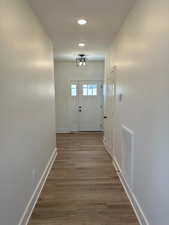 doorway to outside with dark wood-style floors, visible vents, and baseboards