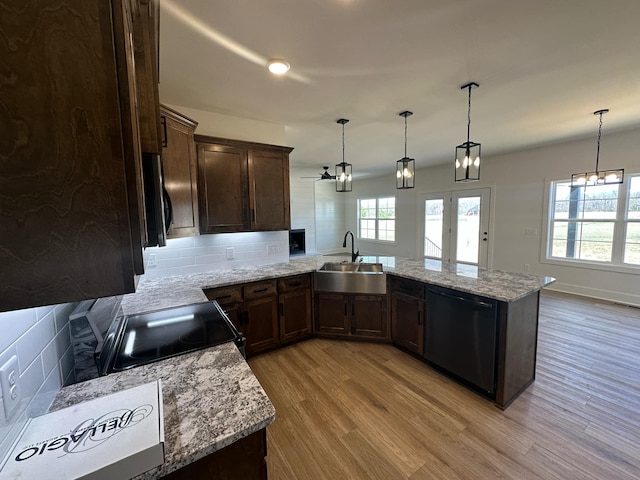 kitchen with light wood-style flooring, a peninsula, a sink, decorative backsplash, and black appliances