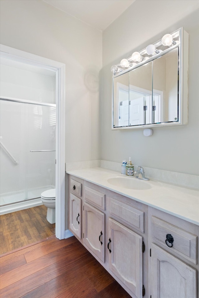 full bath featuring toilet, a stall shower, wood finished floors, and vanity