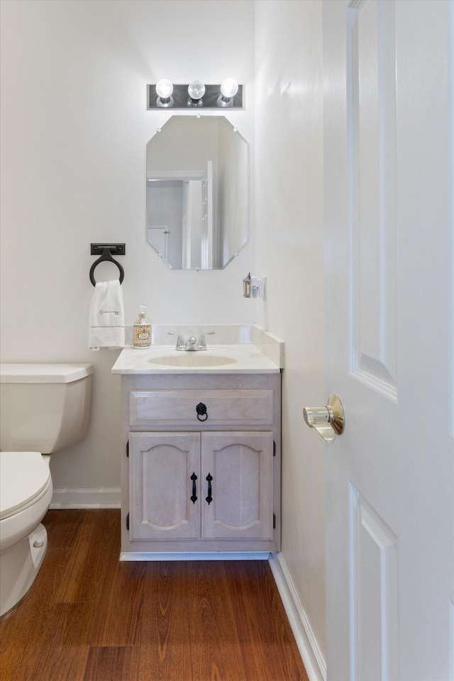 bathroom featuring baseboards, vanity, toilet, and wood finished floors