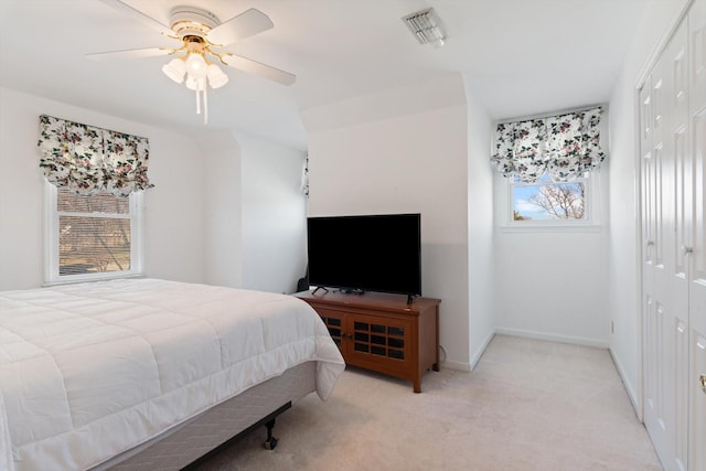 bedroom with ceiling fan, light colored carpet, visible vents, baseboards, and a closet