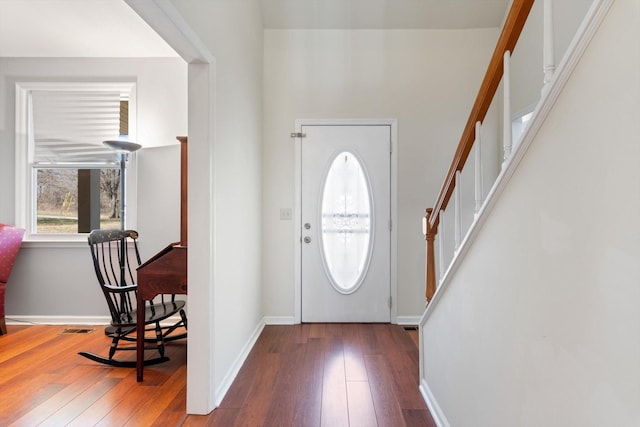 entrance foyer with stairs, hardwood / wood-style floors, visible vents, and baseboards