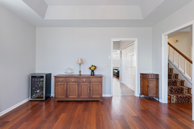 bar featuring dark wood-type flooring, wine cooler, stairway, and baseboards