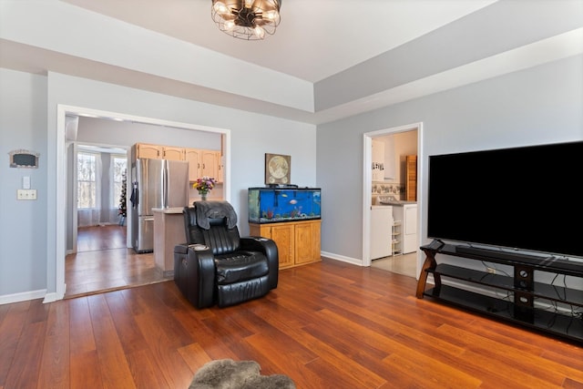 living room with dark wood-type flooring, baseboards, and an inviting chandelier