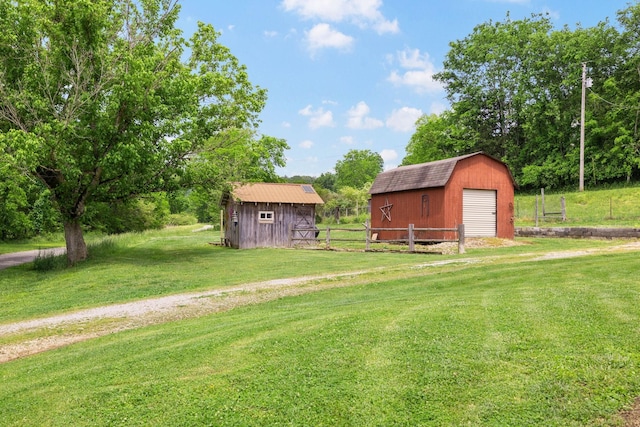 view of yard with fence, a shed, a garage, driveway, and an outdoor structure