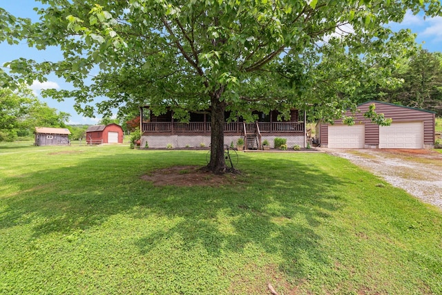 view of front facade featuring an outbuilding, a detached garage, a deck, and a front yard