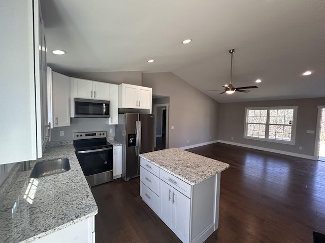 kitchen with light stone counters, dark wood-style floors, stainless steel appliances, lofted ceiling, and white cabinets