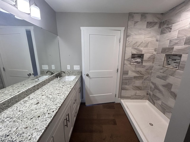 full bath with tiled shower, wood finished floors, and vanity