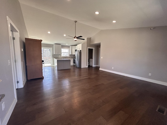 unfurnished living room featuring dark wood-style floors, lofted ceiling, visible vents, and baseboards