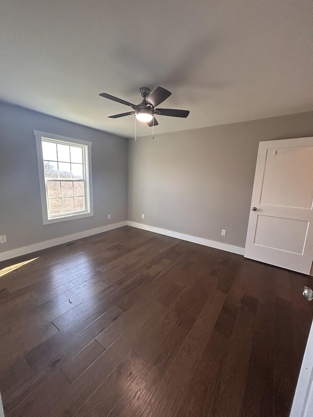 unfurnished room with visible vents, dark wood finished floors, baseboards, and ceiling fan