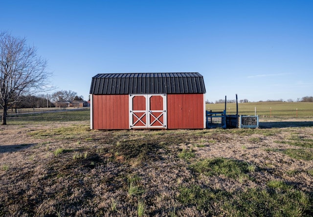 view of outbuilding featuring central air condition unit, a rural view, fence, and an outbuilding