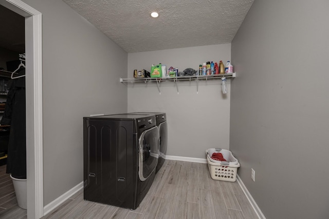 washroom featuring laundry area, baseboards, separate washer and dryer, and light wood-style floors