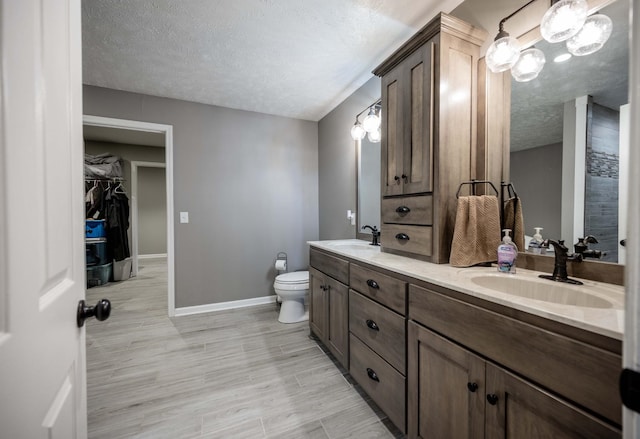 full bathroom featuring a sink, a textured ceiling, baseboards, and double vanity