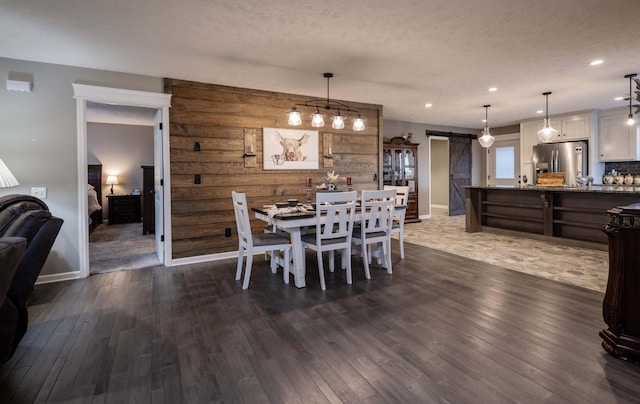 dining room featuring dark wood-type flooring, recessed lighting, a textured ceiling, and a barn door