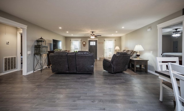 living room with dark wood-type flooring, a ceiling fan, visible vents, and recessed lighting