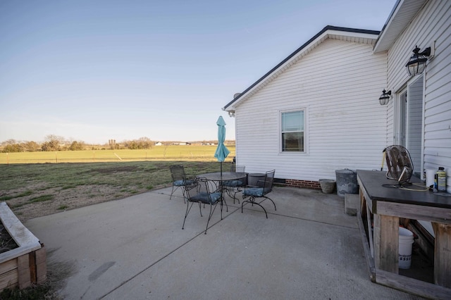 view of patio / terrace with outdoor dining space, a rural view, and fence