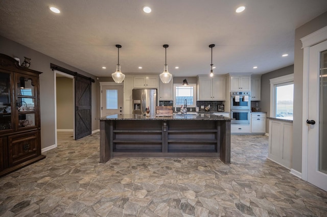 kitchen featuring a barn door, a sink, white cabinetry, appliances with stainless steel finishes, and open shelves