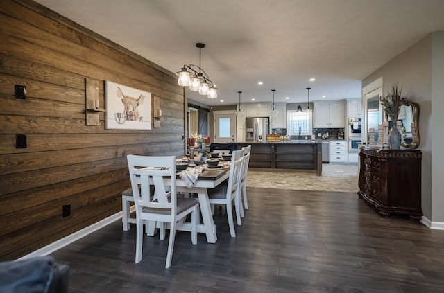 dining room featuring dark wood-style floors, recessed lighting, wooden walls, and baseboards