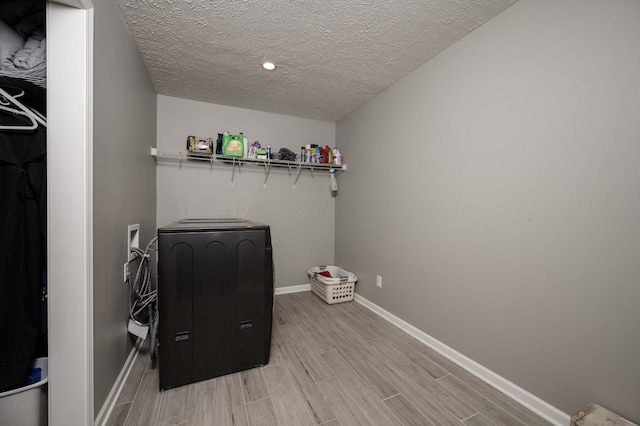 clothes washing area with laundry area, baseboards, a textured ceiling, wood finish floors, and separate washer and dryer