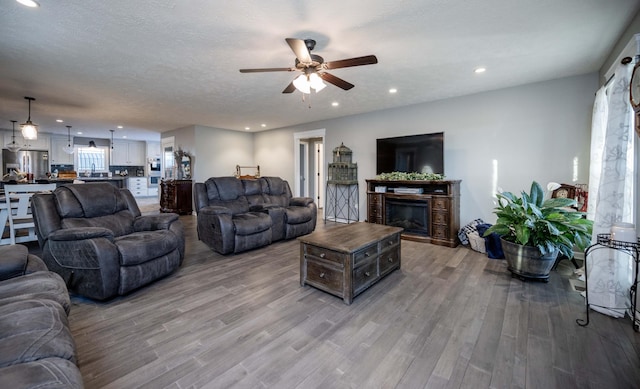 living room with recessed lighting, a textured ceiling, wood finished floors, and a glass covered fireplace