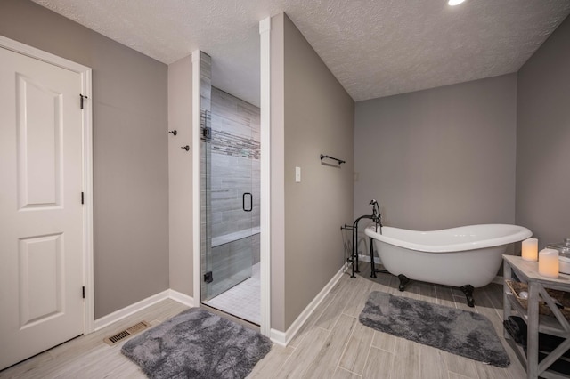 bathroom featuring a stall shower, visible vents, a freestanding bath, and wood tiled floor