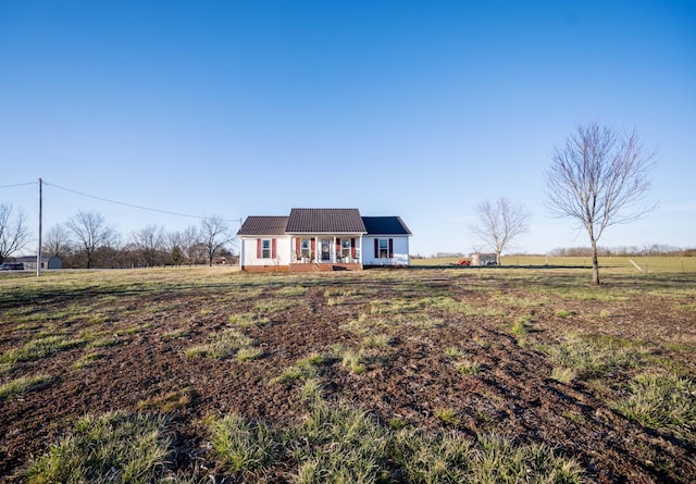 view of front of home with covered porch, a rural view, and metal roof