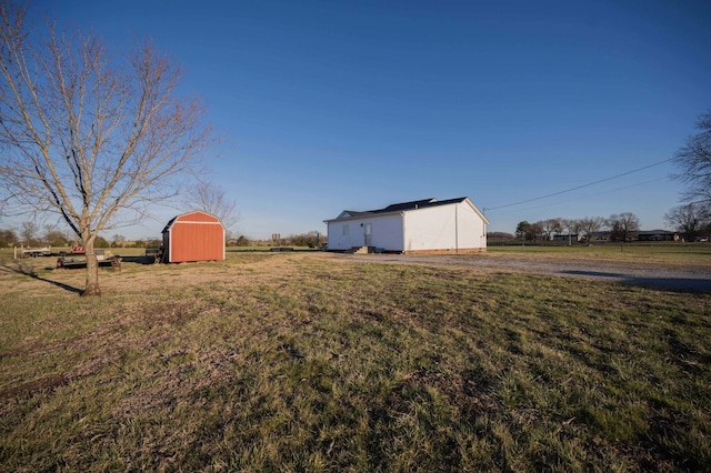 view of yard featuring a rural view, an outdoor structure, and a storage unit