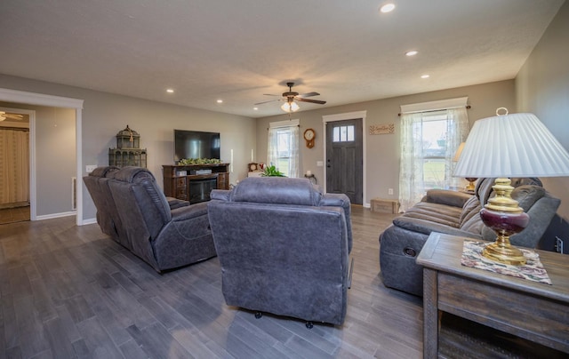 living room with dark wood-style floors, a glass covered fireplace, baseboards, and recessed lighting