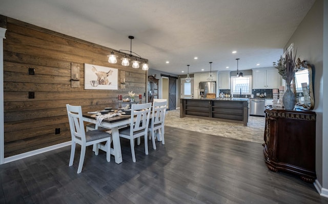 dining space featuring wood walls, a barn door, dark wood-style flooring, and recessed lighting