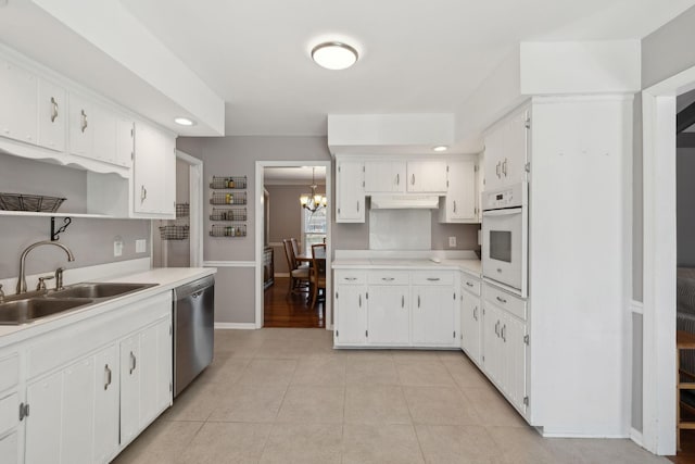 kitchen featuring dishwasher, oven, under cabinet range hood, a sink, and light tile patterned flooring