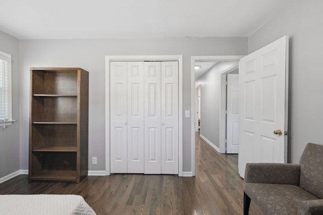 bedroom with a closet, dark wood finished floors, and baseboards