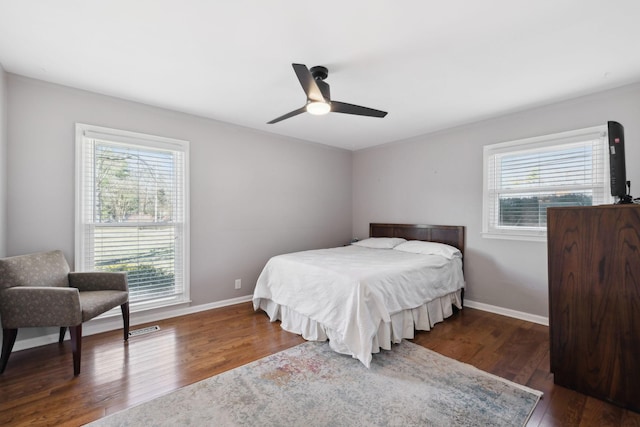 bedroom with multiple windows, baseboards, and wood finished floors