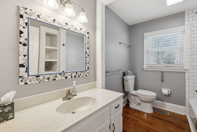 bathroom featuring visible vents, toilet, vanity, wood finished floors, and baseboards