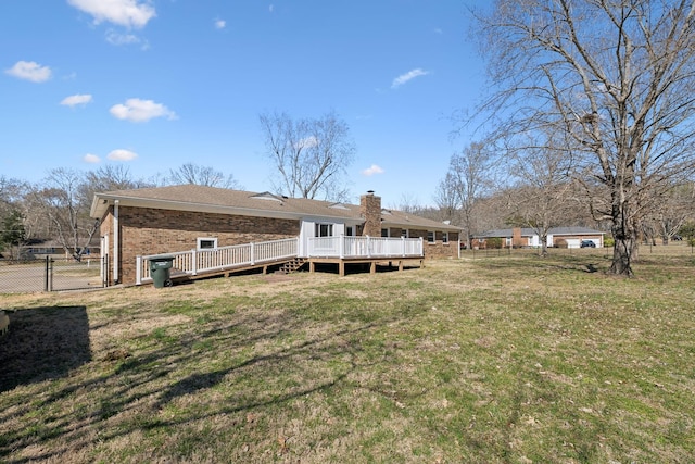 back of property with a yard, a gate, fence, a wooden deck, and brick siding