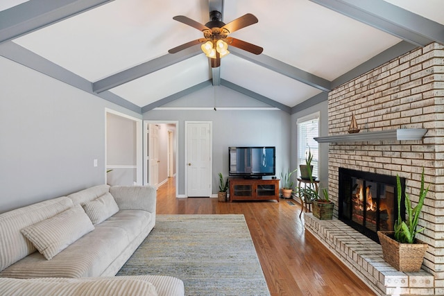 living room featuring ceiling fan, a fireplace, lofted ceiling with beams, and wood finished floors