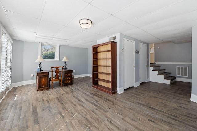 office area with visible vents, a drop ceiling, baseboards, and wood finished floors