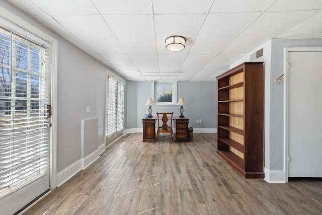 home office with a paneled ceiling, baseboards, visible vents, and wood finished floors