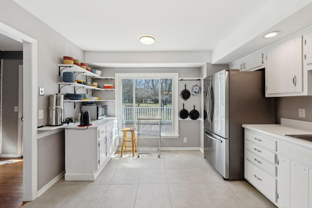 kitchen featuring light tile patterned floors, light countertops, appliances with stainless steel finishes, white cabinetry, and baseboards