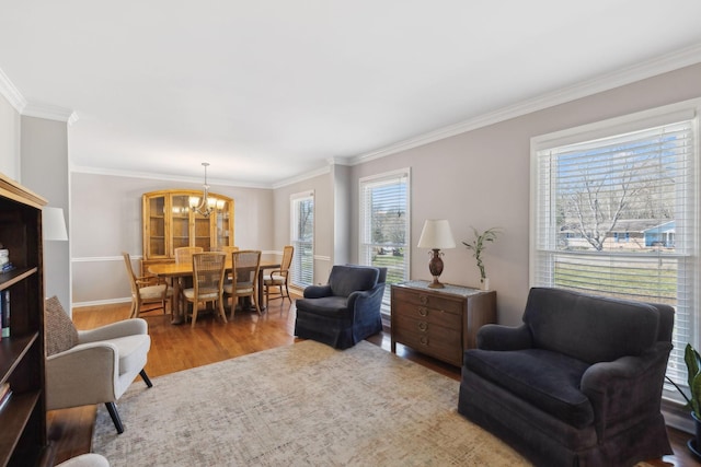 living room featuring baseboards, a notable chandelier, ornamental molding, and wood finished floors