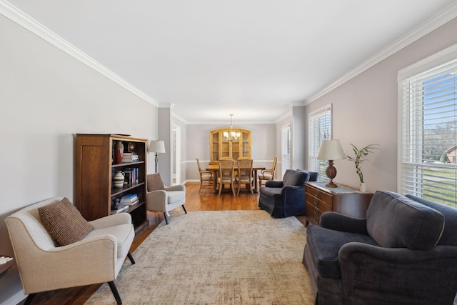 living area featuring a healthy amount of sunlight, crown molding, an inviting chandelier, and wood finished floors