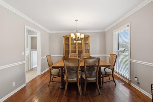 dining area with hardwood / wood-style flooring, visible vents, baseboards, ornamental molding, and an inviting chandelier