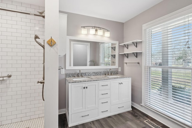 full bathroom with a tile shower, wood finished floors, and a sink