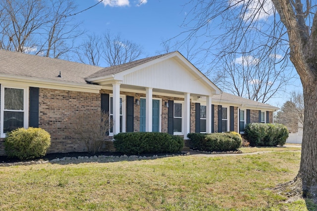 view of front facade featuring brick siding, a front lawn, and a shingled roof