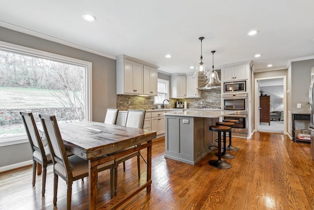 dining room featuring baseboards, ornamental molding, wood finished floors, and recessed lighting